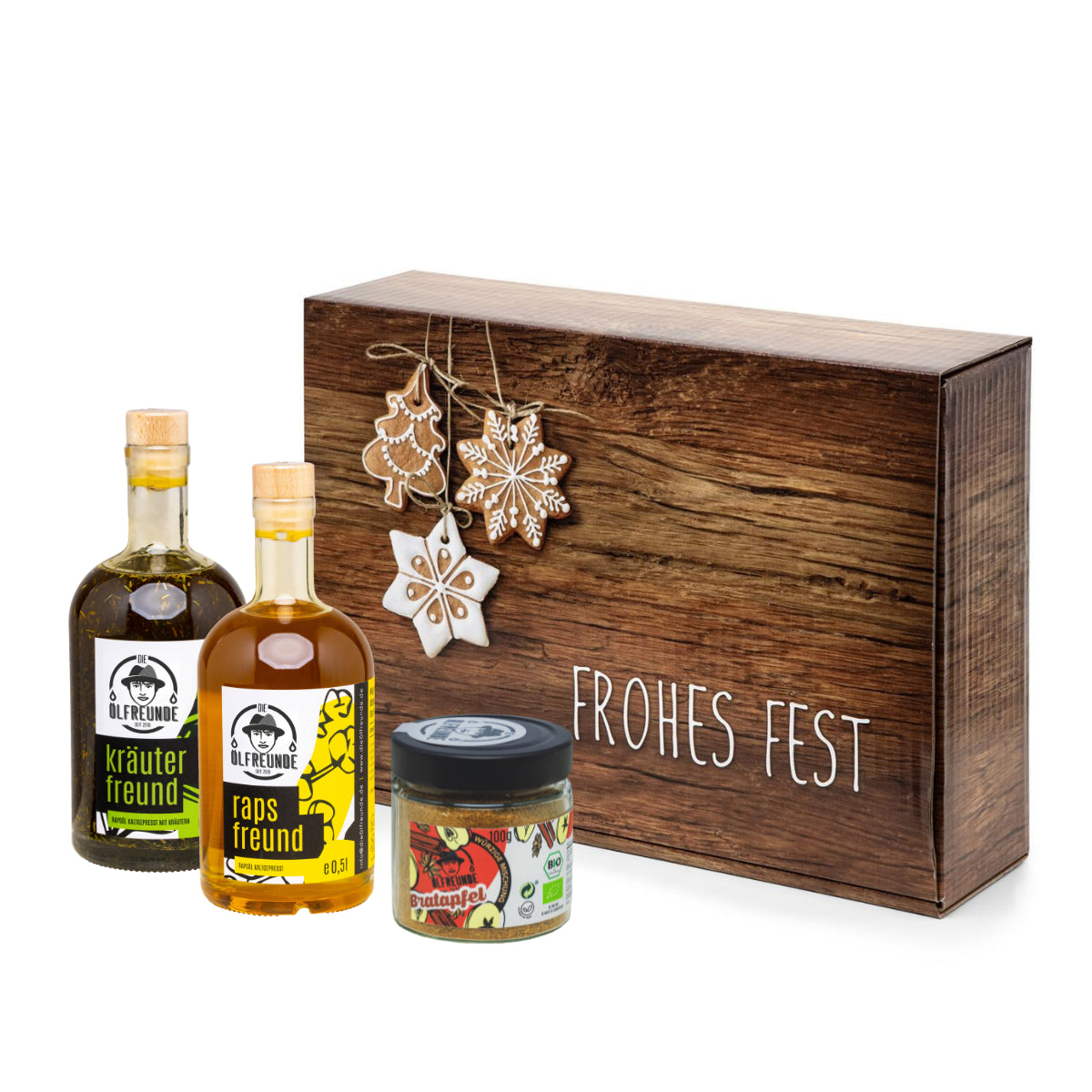 Eine Flasche Kräuteröl, Rapsöl und ein Glas Bratapfel-Gewürzmischung der Marke Die Ölfreunde, vor einer Weihnachts-Geschenkeverpackung.