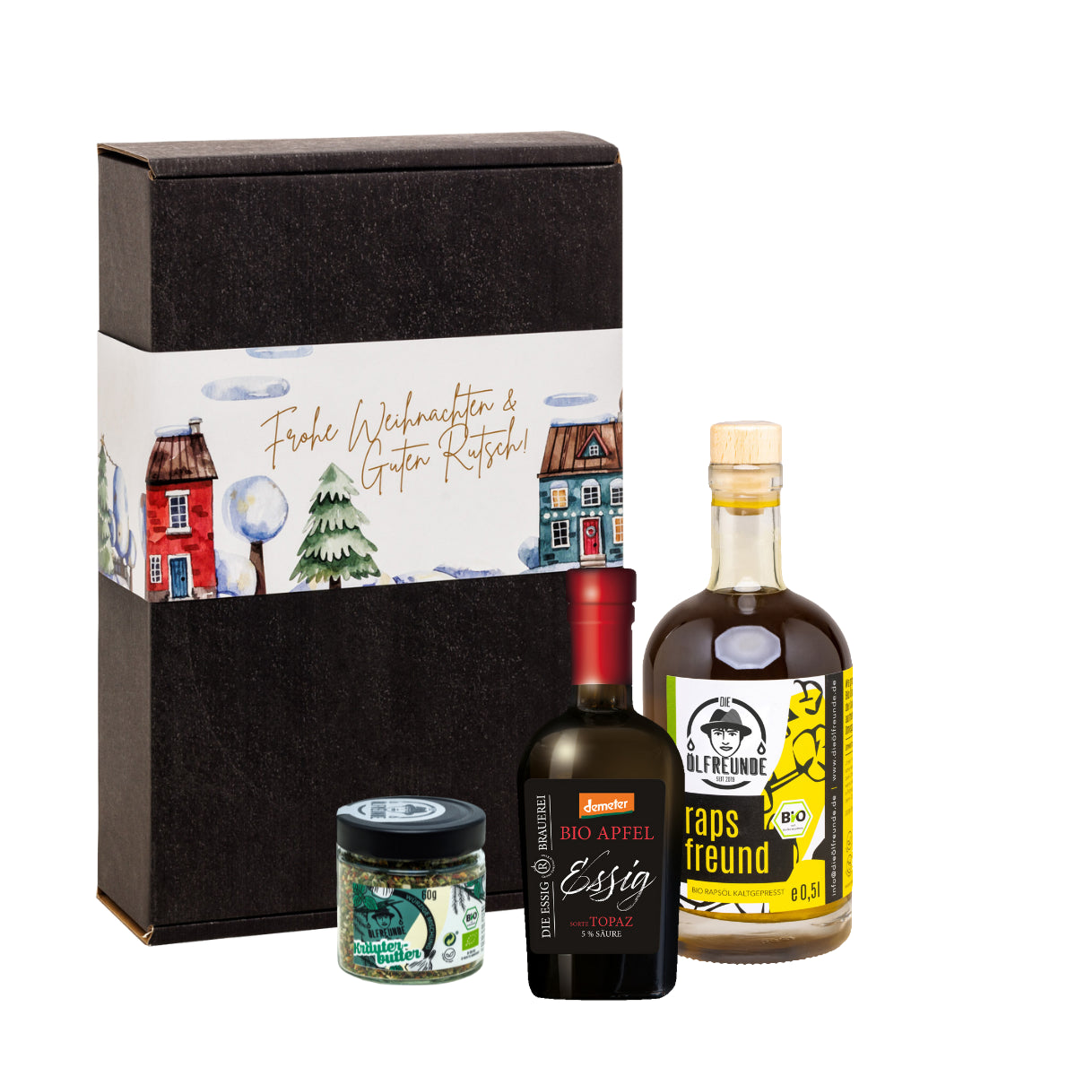 Eine Flasche Rapsöl und ein Glas Kräuterbutter-Gewürzmischung der Marke Die Ölfreunde und eine Flasche Apfelessig der Marke Die Essig Brauerei, vor einer Weihnachts-Geschenkeverpackung.