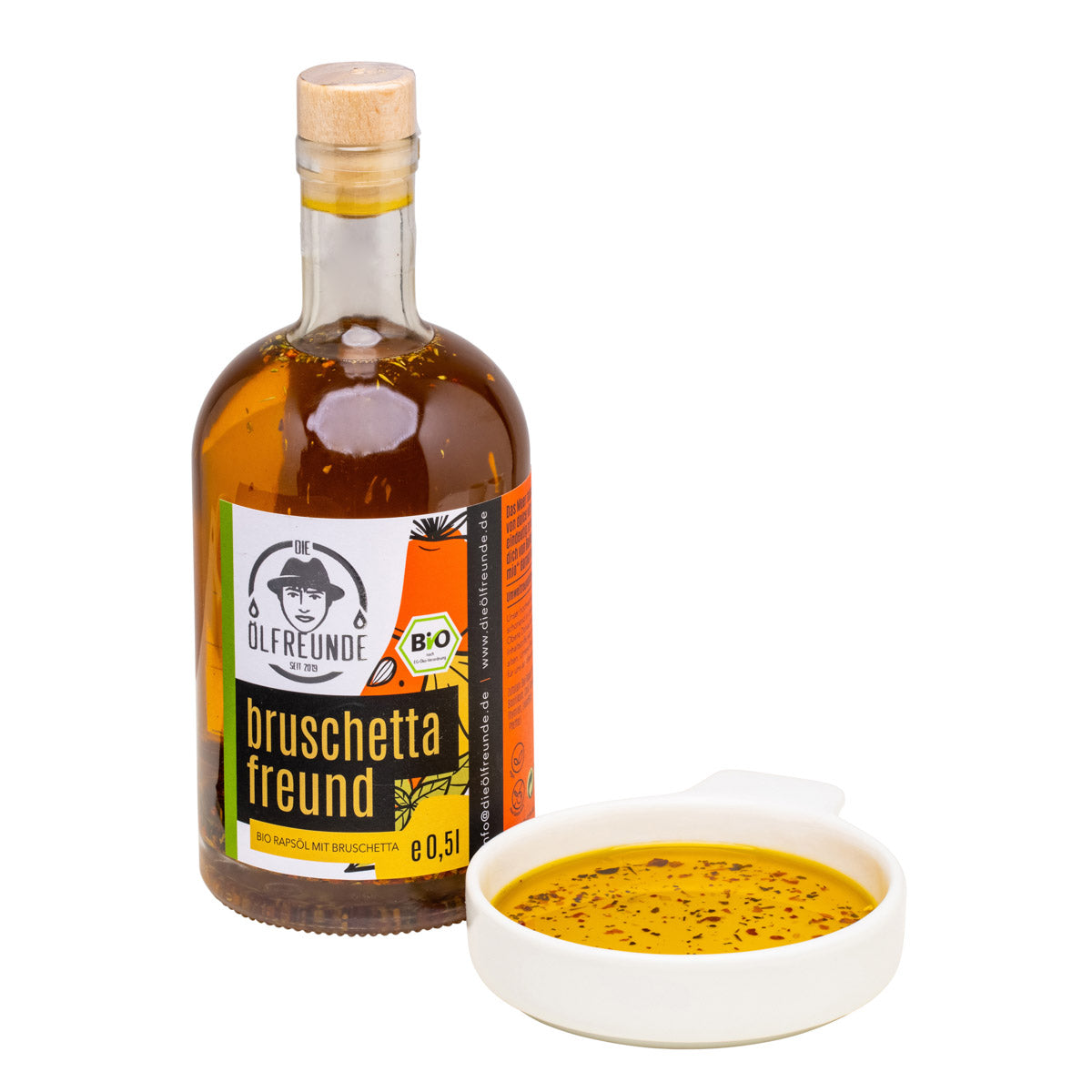 Eine Flasche mit 500ml kaltgepresstes Bio-Rapsöl mit Bruschettagewürz von Marke Die Ölfreunde, daneben eine Schale mit Bruschetta-Öl.