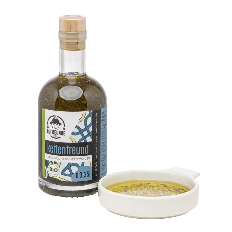 Eine Flasche mit 350ml Bio-Leindotteröl mit Gewürzen der Marke Die Ölfreunde, daneben eine Schale mit diesem Öl.