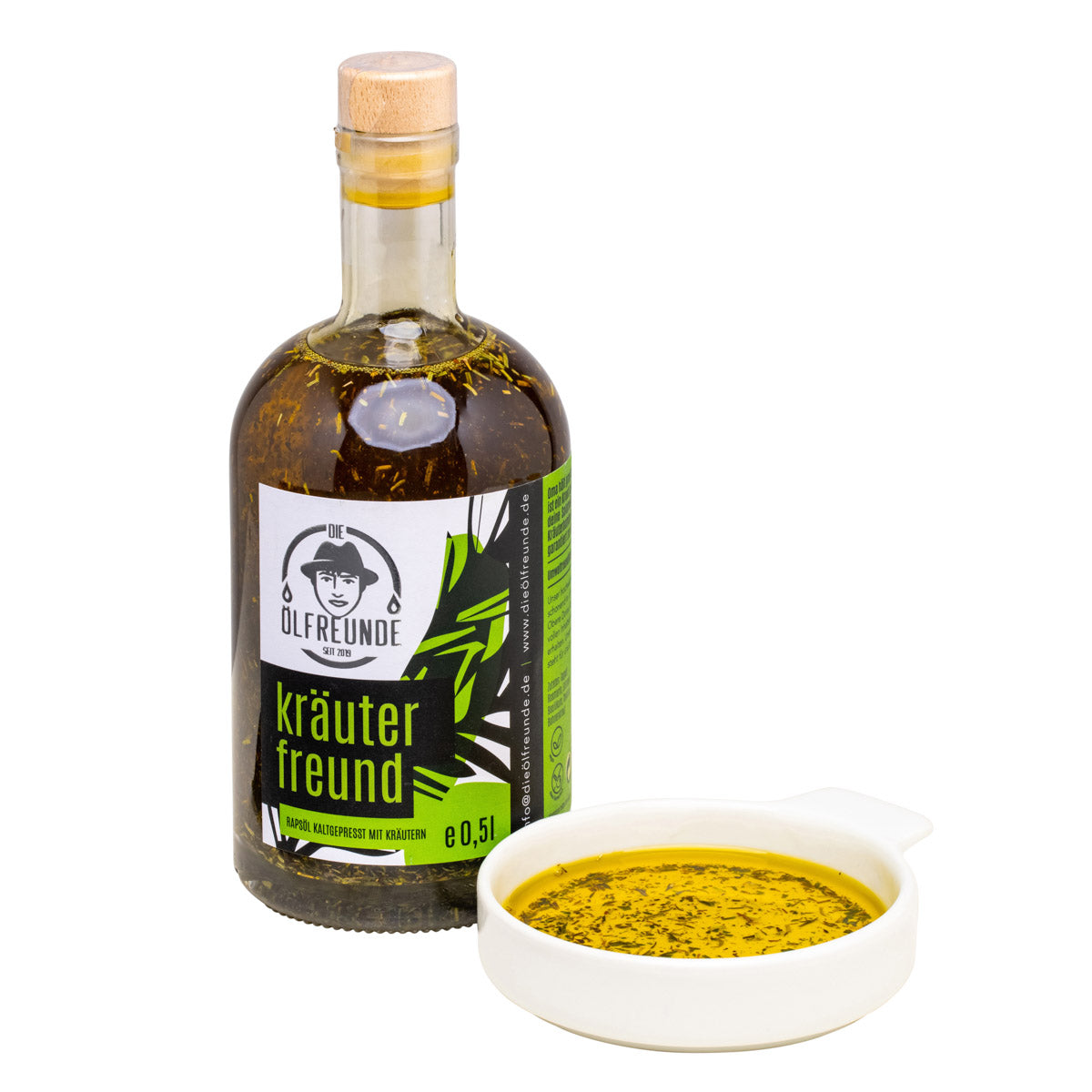 Eine Flasche mit 500ml kaltgepresstes Rapsöl mit Kräutern wie Rosmarin, Estragon, Basilikum, Thymian und Bohnenkraut von Marke Die Ölfreunde, daneben eine Schale mit Kräuteröl.