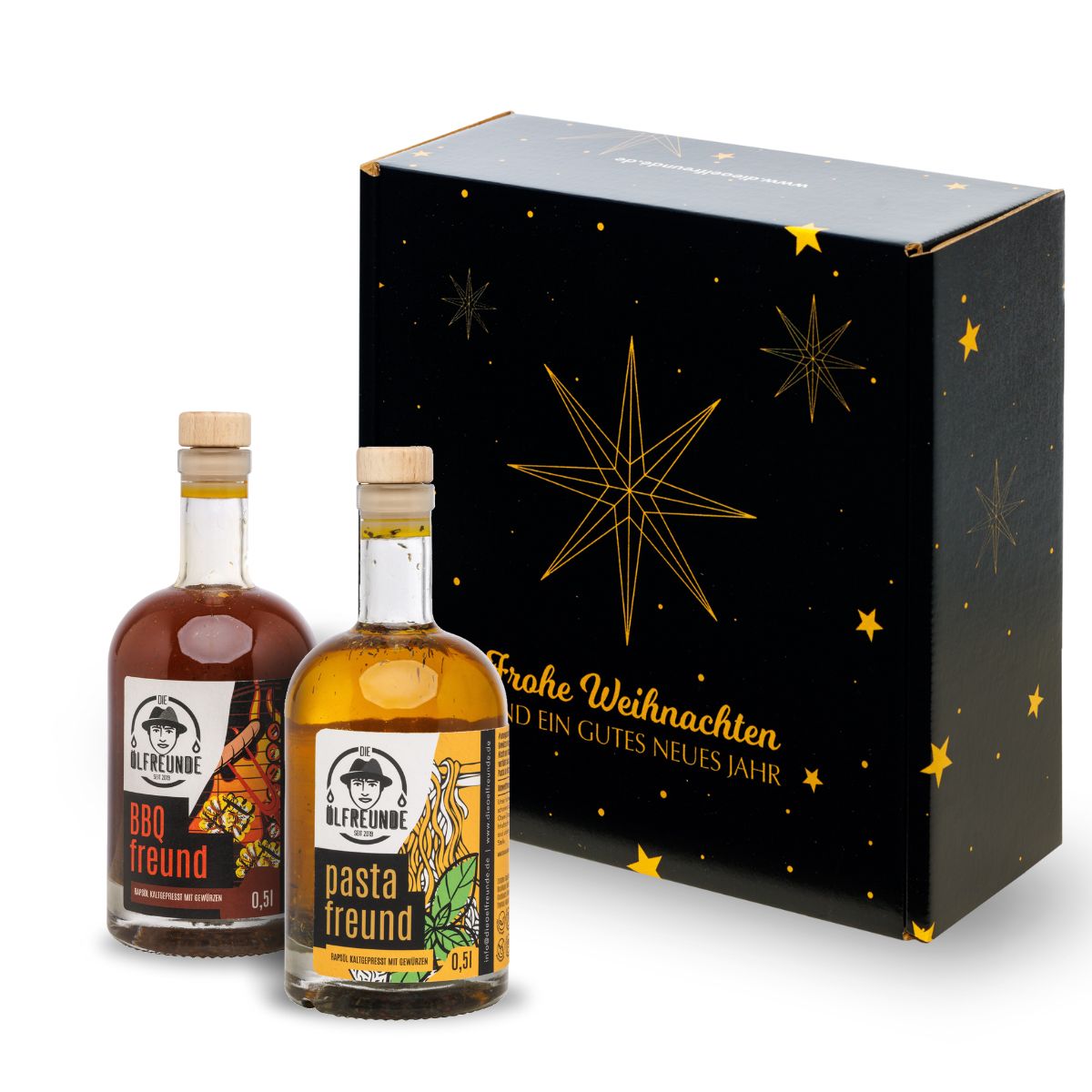 Eine Flasche BBQ-Öl und eine Flasche Pasta-Öl der Marke die Ölfreunde vor einer Weihnachts-Geschenkverpackung.