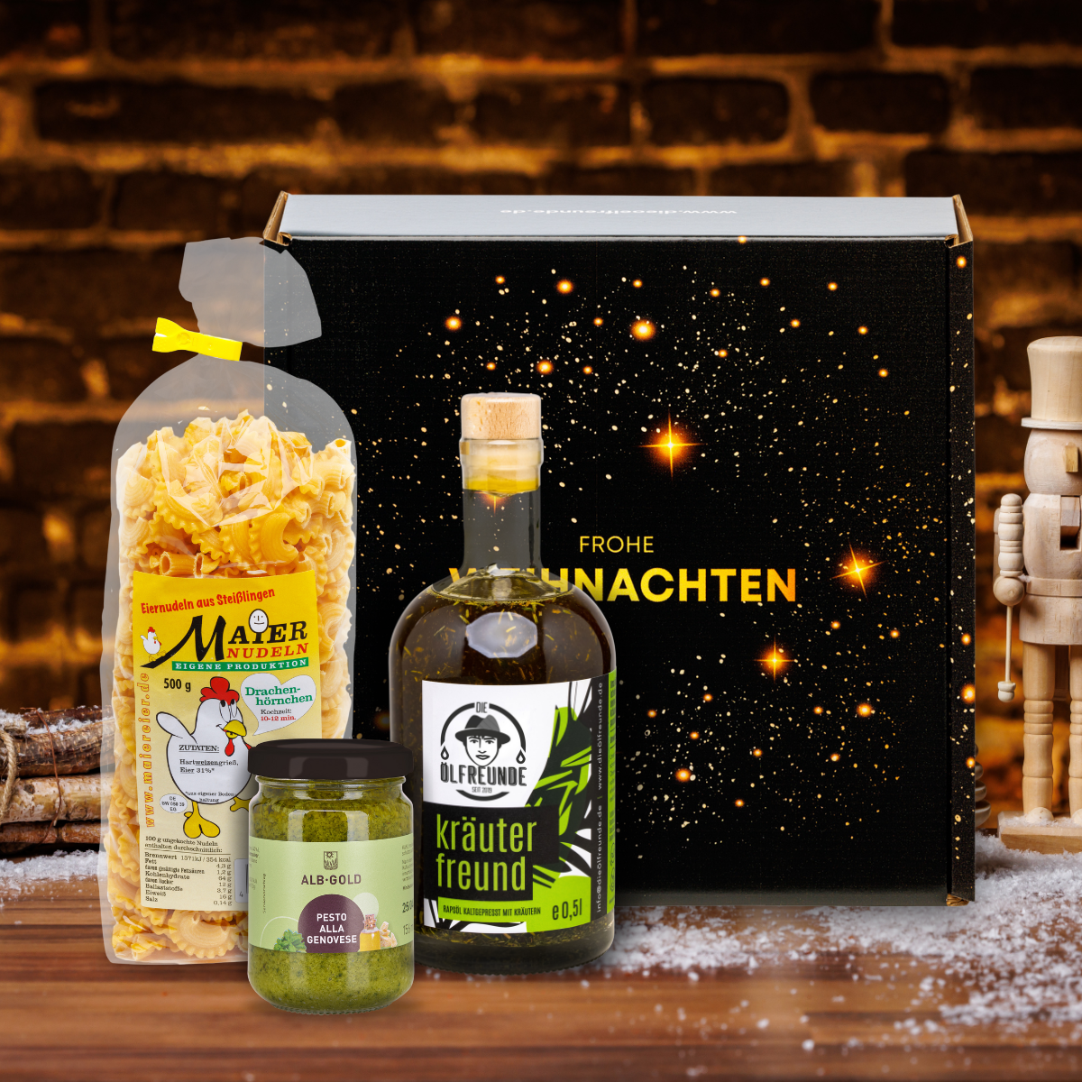 Kräuteröl sowie Eiernudeln und Pesto alla Genovese vor einer Weihnachts-Geschenkverpackung, neben einem Bündel Holz.