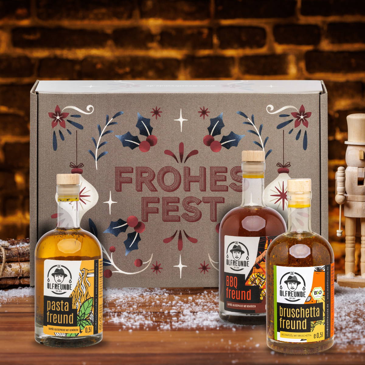 Pasta-Öl, BBQ-Öl und Bruschettaöl der Marke Die Ölfreunde, vor einer Weihnachts-Geschenkeverpackung und dunklem Hintergrund.
