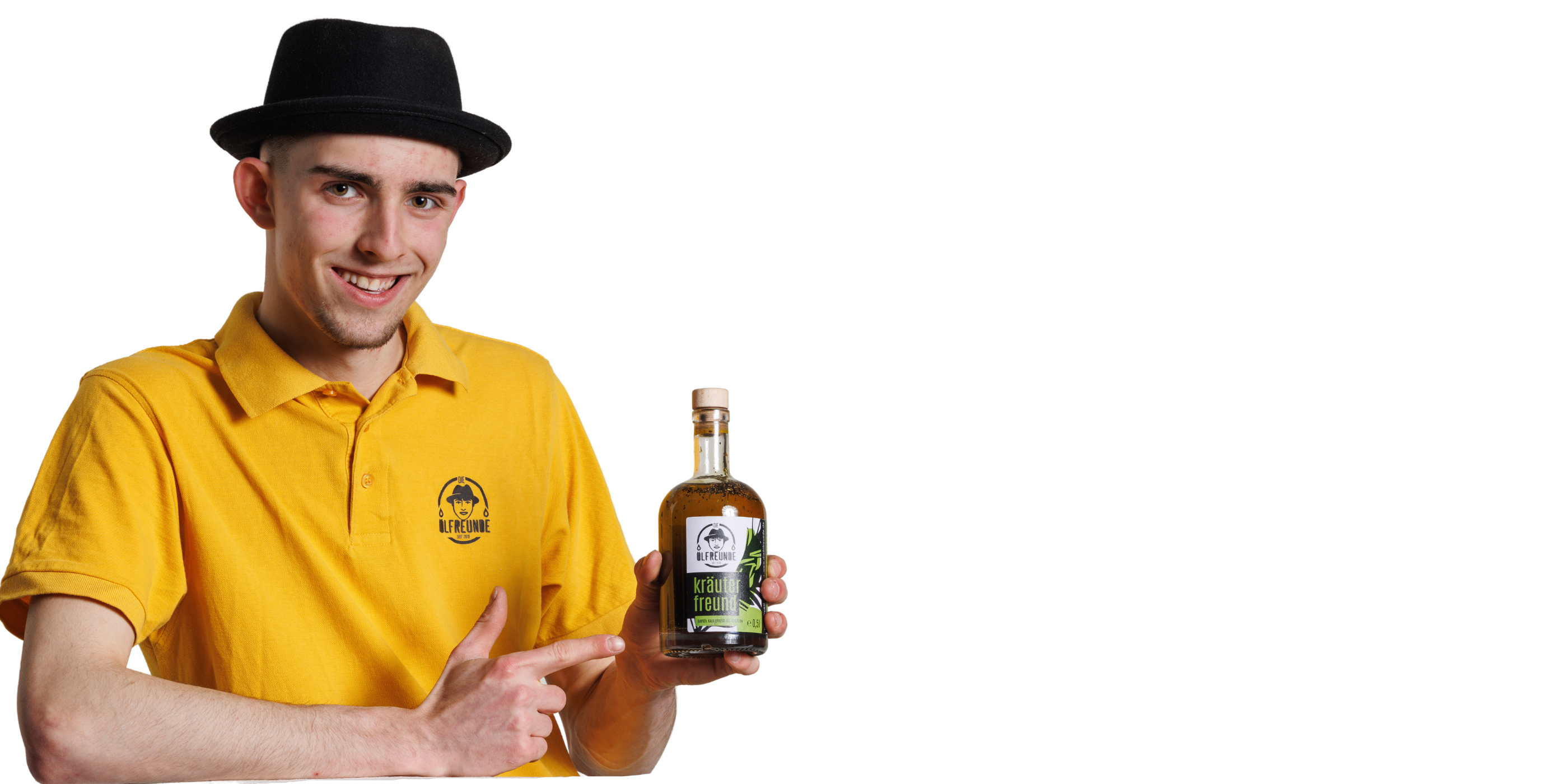 Eine Person mit schwarzem Hut und gelben T-Shirt mit dem Logo der Ölfreunde drauf, hält eine Flasche Kräuteröl der Marke Die Ölfreunde in der Hand. Die andere Hand zeigt auf die Flasche.