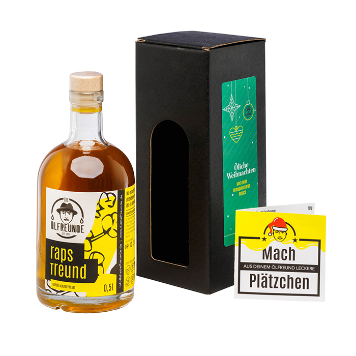 links steht eine Flasche Rapsöl mit gelben Etikett, in der Mitte ein schwarzer Karton und eine Sichtfenster mit einem grünen Weihnachtsaufkleber an der Seite, Rechts ein kleines Rezept mit der Aufschrift Mach aus deinem Ölfreund leckere Plätzchen.