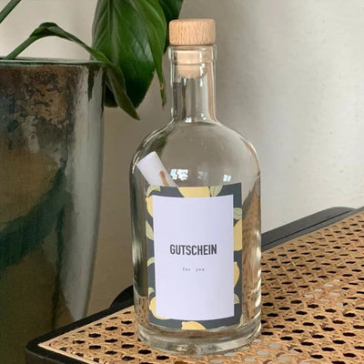 Eine leere Ölflasche mit dem Etikett 'Gutschein' und einem Brief in der Flasche.