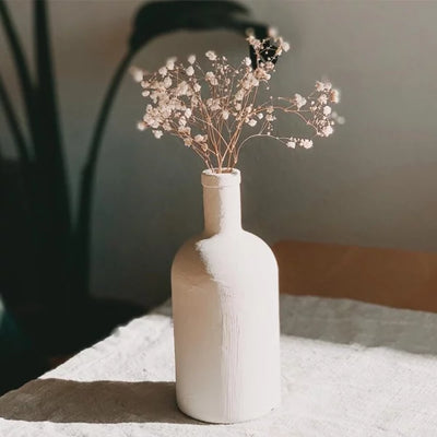 Eine Vase in Stein und Flaschenoptik mit rosa farbigen Schleierkraut