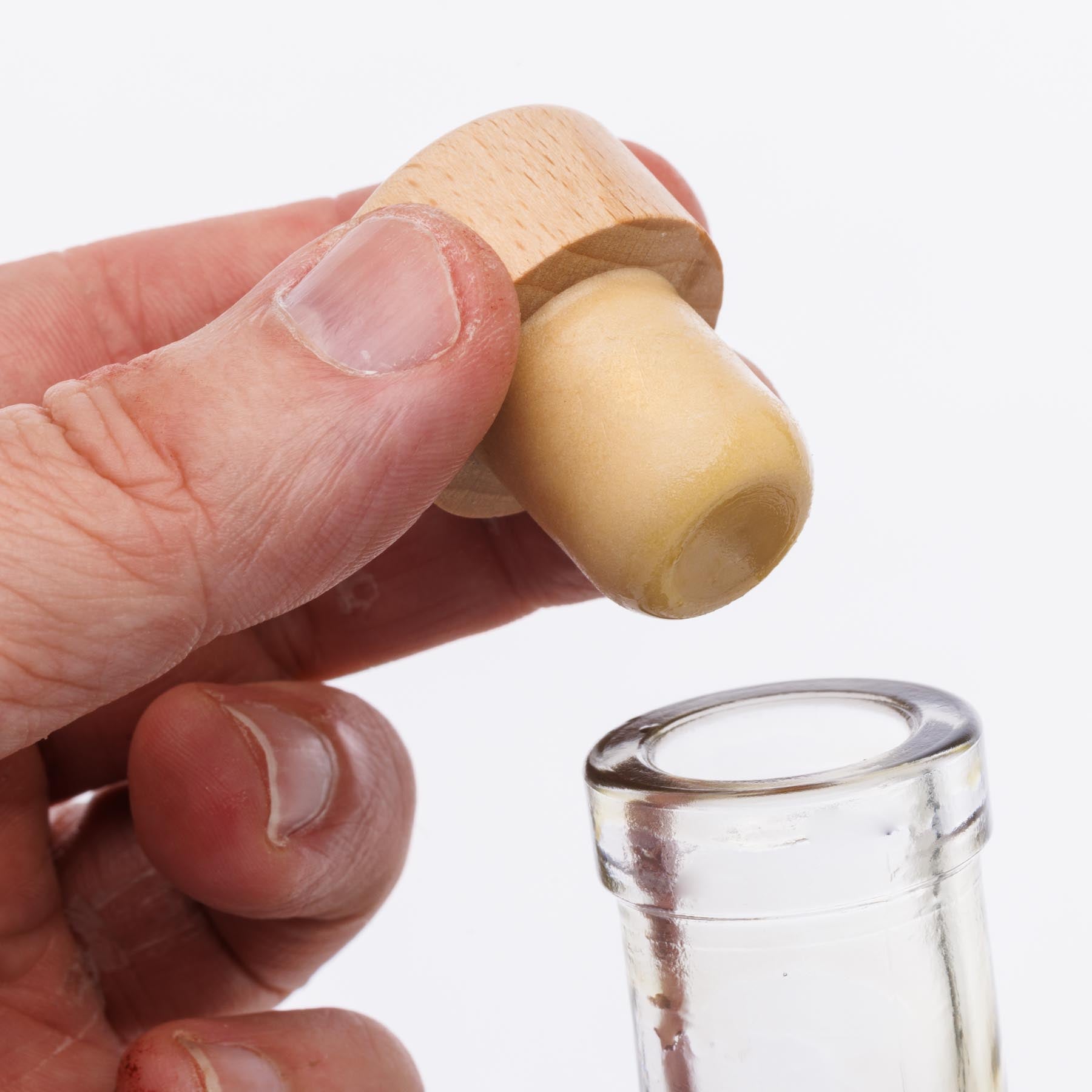 Nahaufnahme eines Glasflaschenhalses. Eine Hand hält den Holzgriffkorken über der Flaschenöffnung ohne Ausgießer.