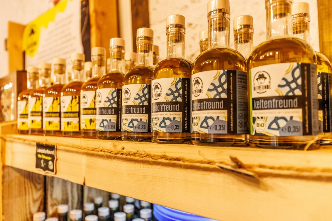Ein Regal mit mehreren Flaschen 'Keltenfreund' und 'Leindotterfreund' der Marke Die Ölfreunde. Darunter ist ein Preisschild in schwarz zu sehen.