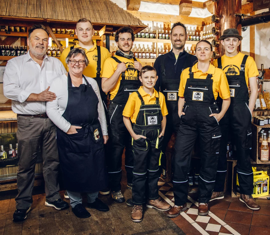 Ein Familienunternehmen in einem rustikalen Gebäude – das Team steht vor einer Holztheke, umgeben von einem vielfältigen Sortiment an Produkten.