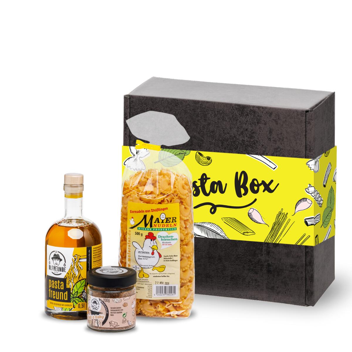 Eine Flasche Pasta-Öl, ein Glas Salt it Baby Rauchsalz von der Marke Die Ölfreunde und Nudeln der Marke Maier Nudeln, vor einer Box mit Aufschrift ,Pasta Box'.