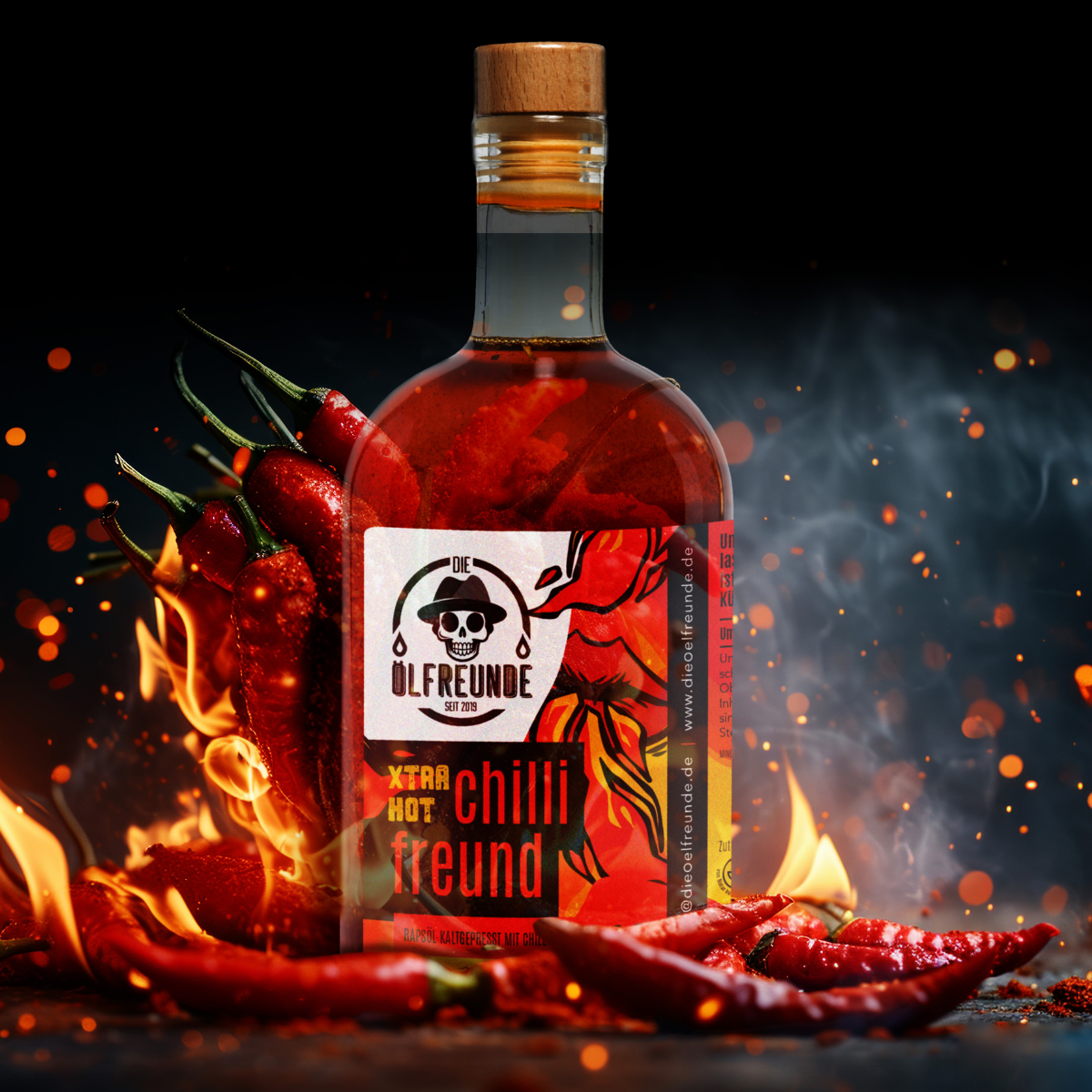 Eine Flasche Chilli Öl extra hot Der Marke Die Ölfreunde, umgeben von brennenden roten Chilischoten auf dunklem Hintergrund mit Glut und Rauch.